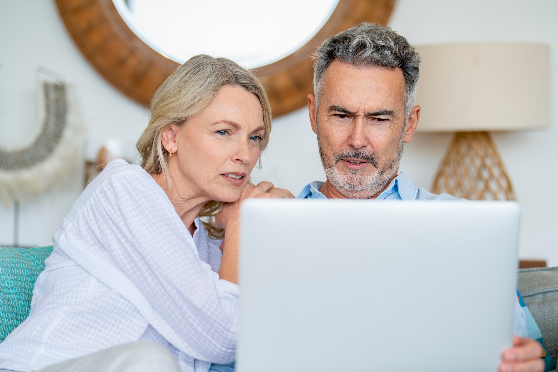 Middelbaar koppel geconcentreerd bezig met het plannen van een roadtrip op een laptop