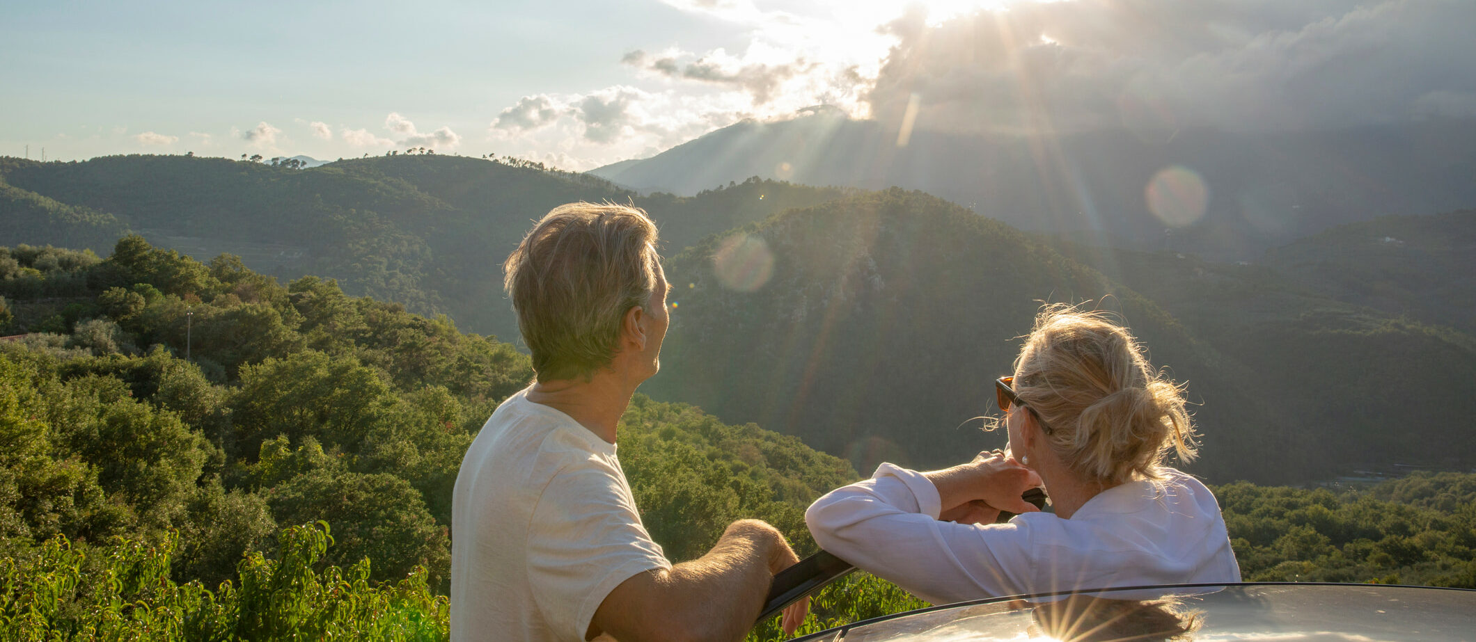 50+ stel ontspant bij een auto tijdens zonsopgang op een rustige plek