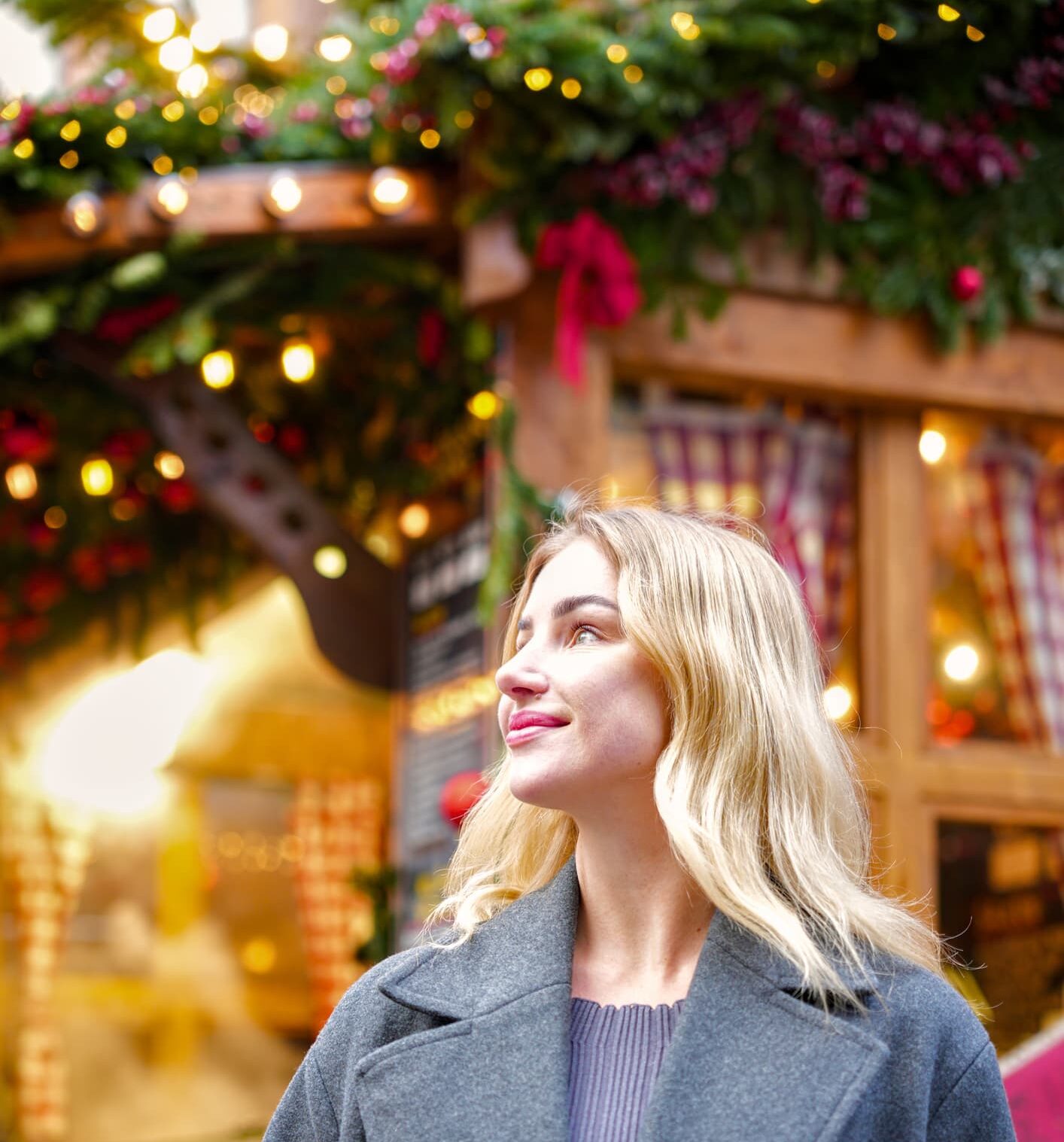 Blonde woman walking at Christmas market with festive decorations